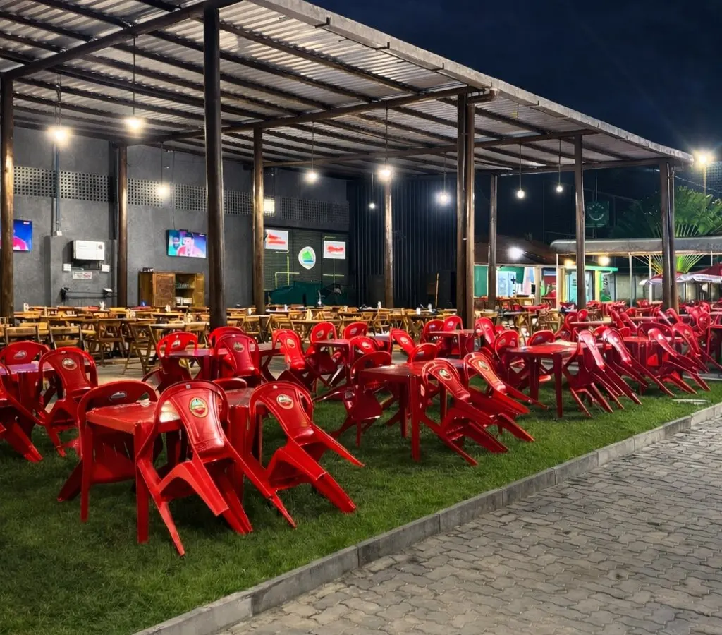 Área externa coberta da Arena com mesas sobre o gramado à noite