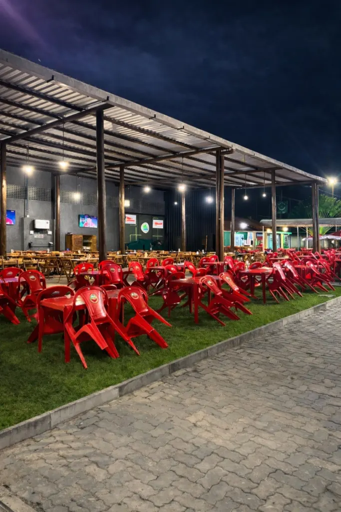 Área externa coberta da Arena com mesas sobre o gramado à noite