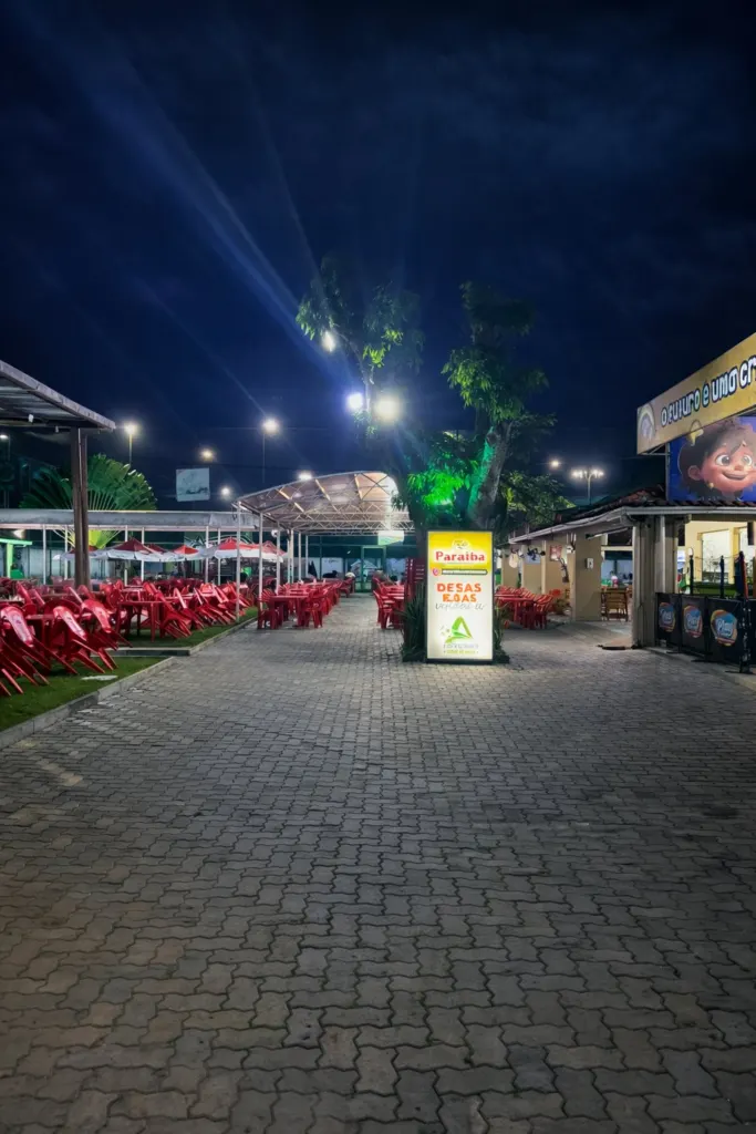 Caminho iluminado entre as mesas e o Play Parque à noite